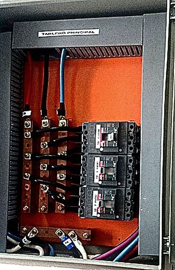 Tablero eléctrico abierto con interruptores y placa naranja