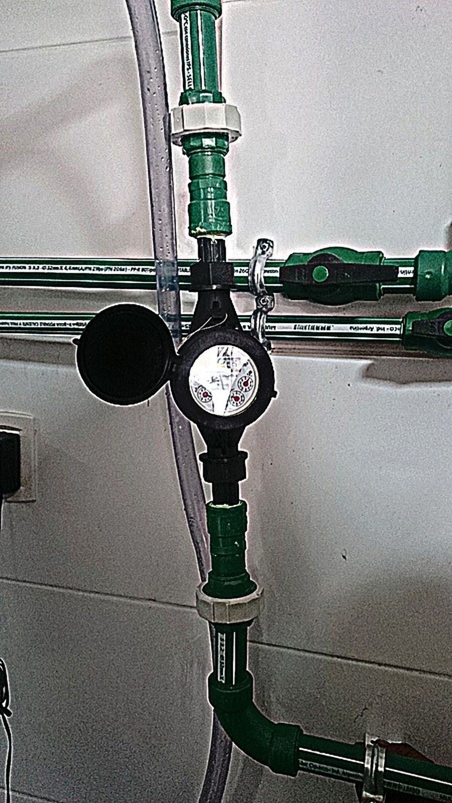 Tubería verde con medidor sobre una pared