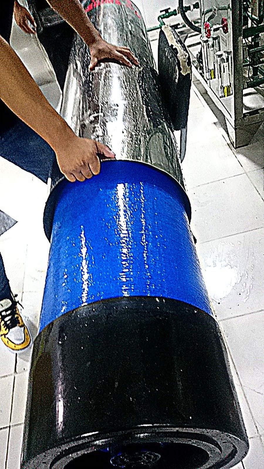 Persona sosteniendo una tubería grande con recubrimiento azul y negro