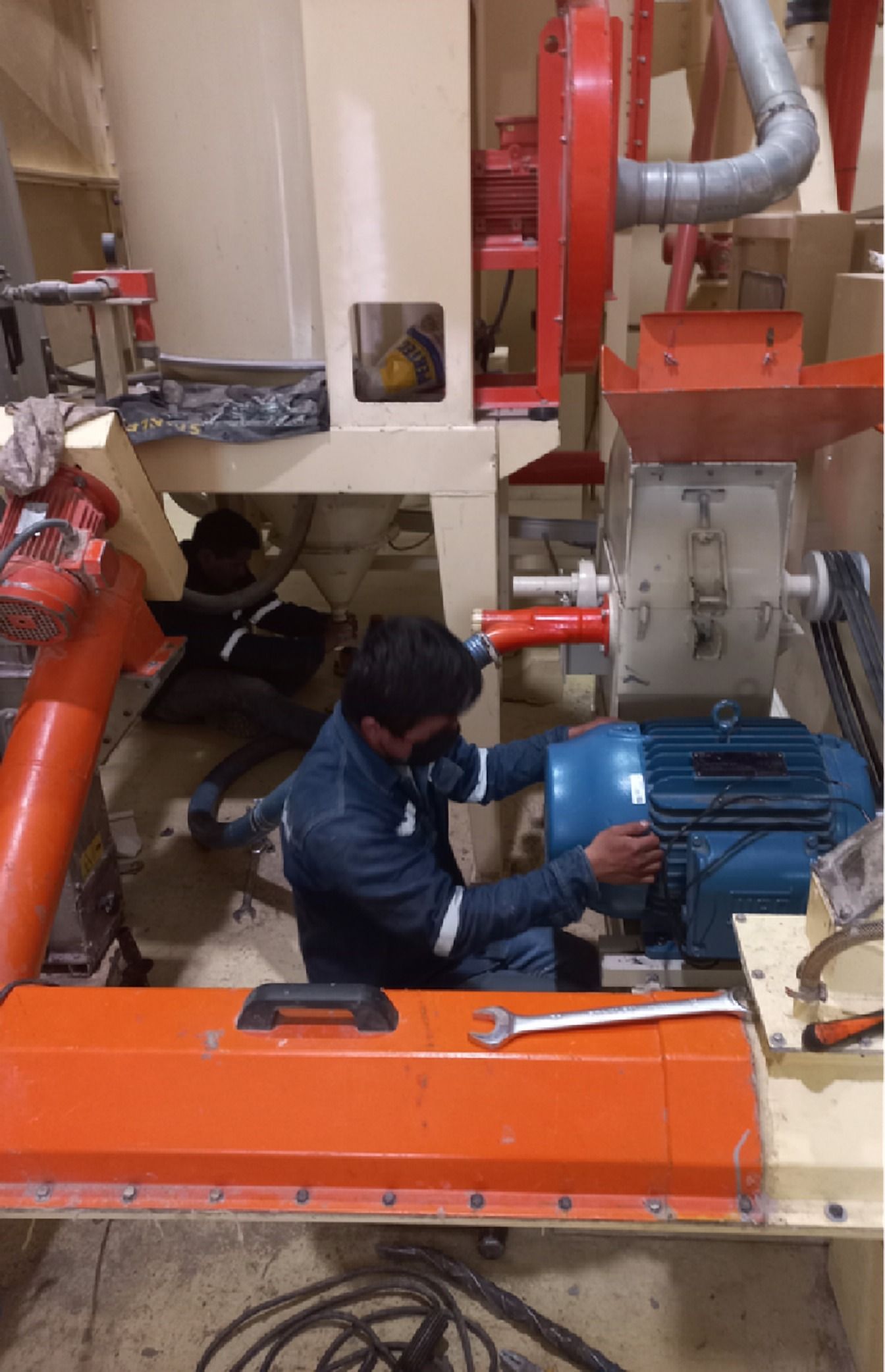 Técnico junto a un motor azul con protección naranja
