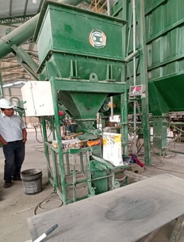 Estructura verde con tolva, con una persona al costado