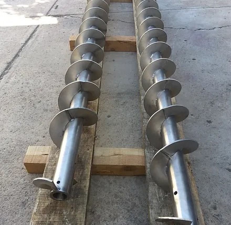 Dos tornillos helicoidales metálicos sobre tablones de madera